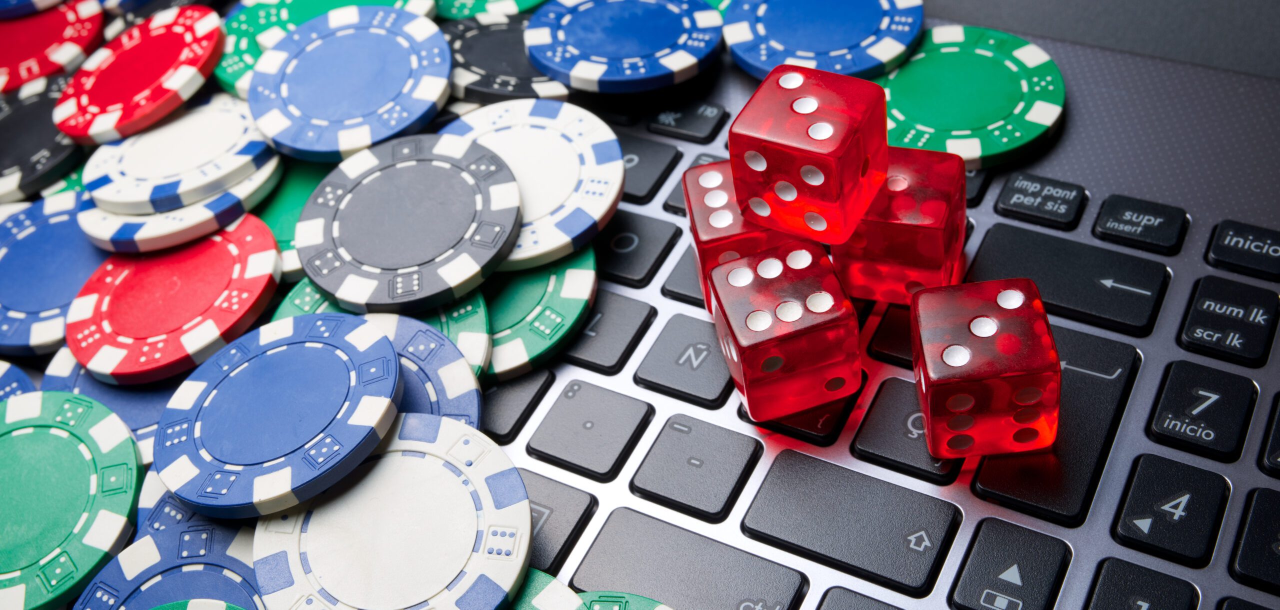 A computer laptop covered in poker chips and red dice.